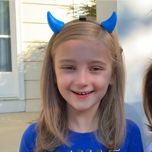 little girl smiling in blue shirt and blue devil horns