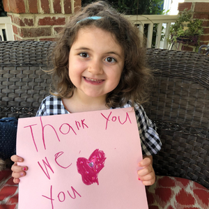 little girl holding sign that says thank you we love you