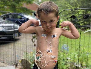 little boy with heart monitors in a strong pose