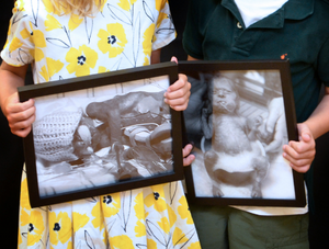 girl and boy holding black and white photos of themselves as babies after heart surgery